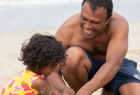 Homme jouant avec sa fille dans le sable sur une plage
