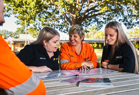 Trois employées de Rio Tinto souriantes, assises à une table sous un arbre