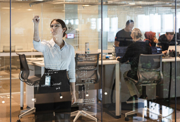 Employée de Rio Tinto dans un centre de haute technologie, écrivant sur un tableau de verre