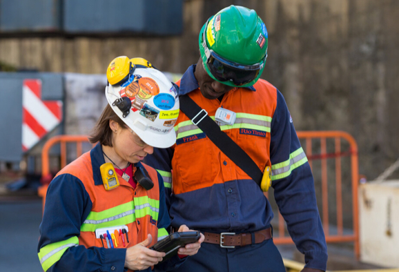 Deux employés de Rio Tinto, un homme et une femme, regardant une tablette électronique sur le site d’un projet